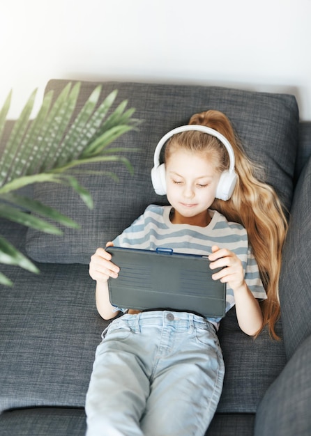 Little girl with headphones and tablet at home