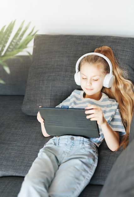 Little girl with headphones and tablet at home