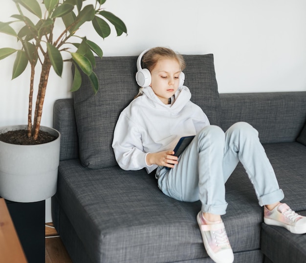 Little girl with headphones and tablet at home