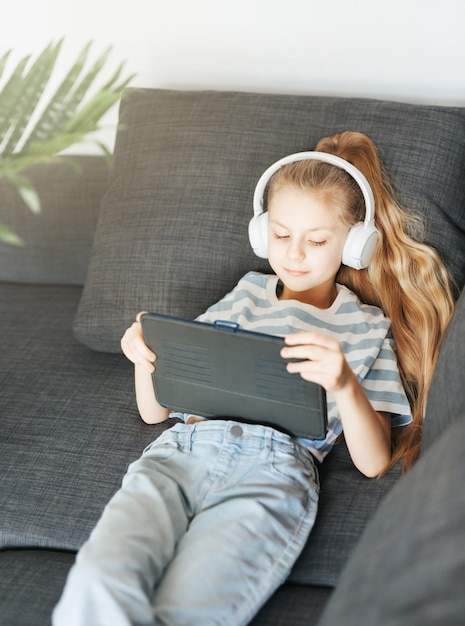 Little girl with headphones and tablet at home