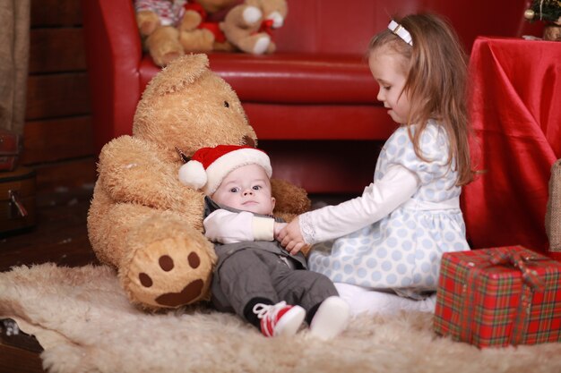 Little girl with her baby brother sitting near a Christmas gifts. new year holiday. Family, happiness, holidays, Christmas concept.