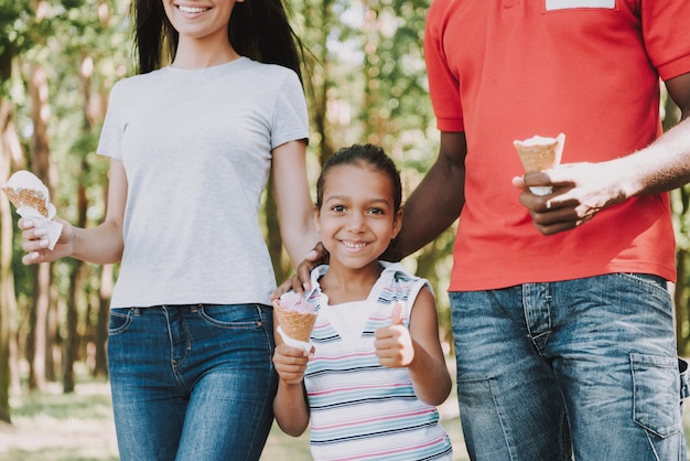 Little girl with her parents eating ice cream in the forest.