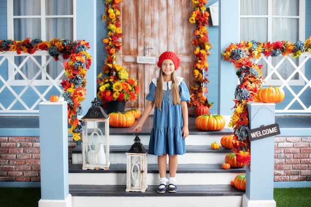 Little girl with lantern while stand on house porch and waiting to trick or treat on Halloween