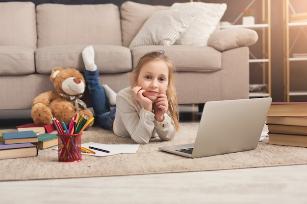 Little girl with laptop at home. Cute child doing homework on computer. Modern online education, communication and technology concept, copy space