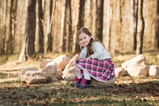 little girl with long hair sitting in the forest