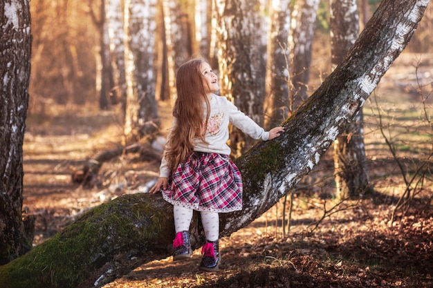 little girl with long hair sitting in the forest