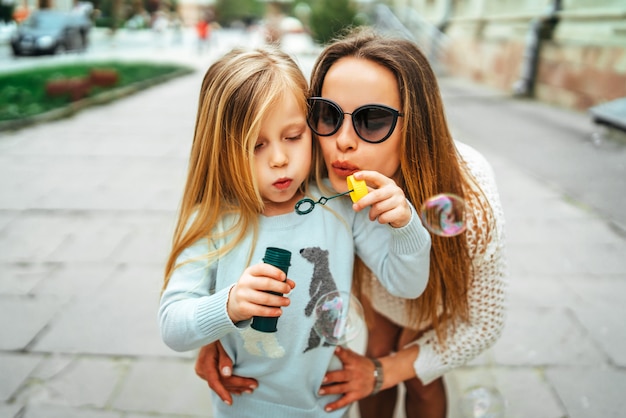 Little girl with mother blowing bubbles outdoor