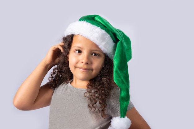 Little girl with Mrs. Claus green hat on gray