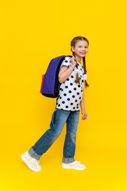 A little girl with pigtails and a briefcase in her hands smiles very happily education at school and additional classes after lessons getting iterative and useful knowledge in high school