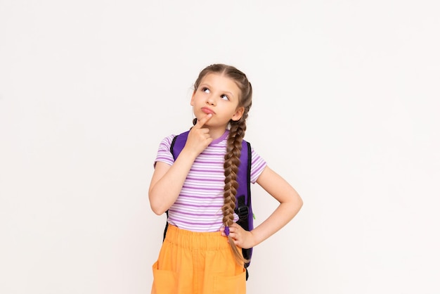 A little girl with pigtails and shorts with a school backpack on her back on a white isolated background Preparatory summer courses for children