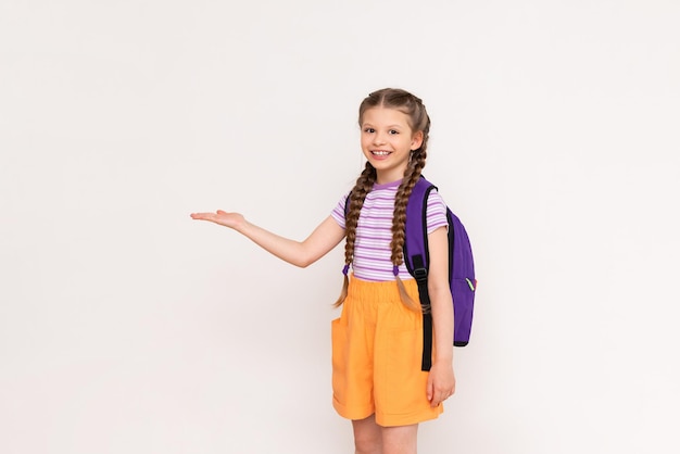 A little girl with a satchel behind her back holds your advertisement on a white isolated background on her hand