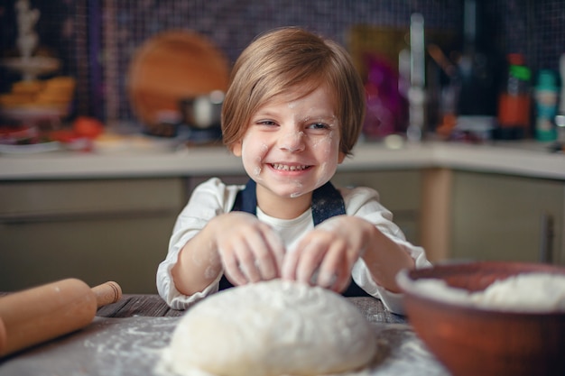 Little girl with short hair kneading dough in the kitchen