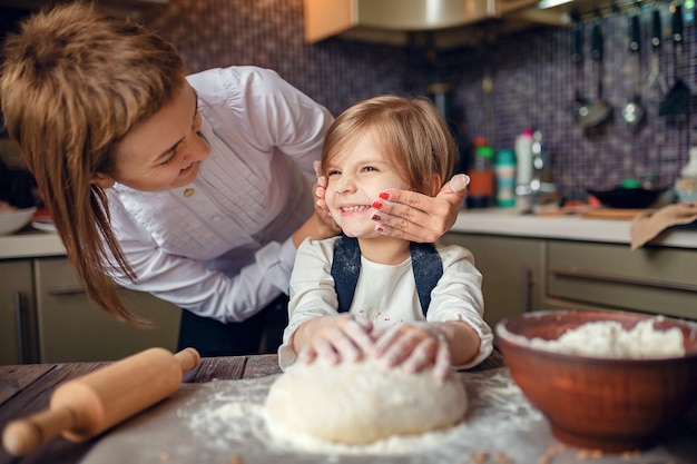 Little girl with short hair kneading dough in the kitchen