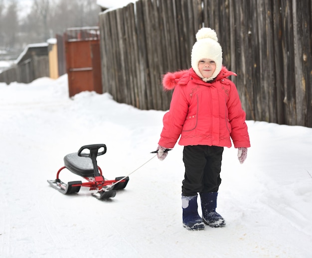 Little girl with sled uphill climbs