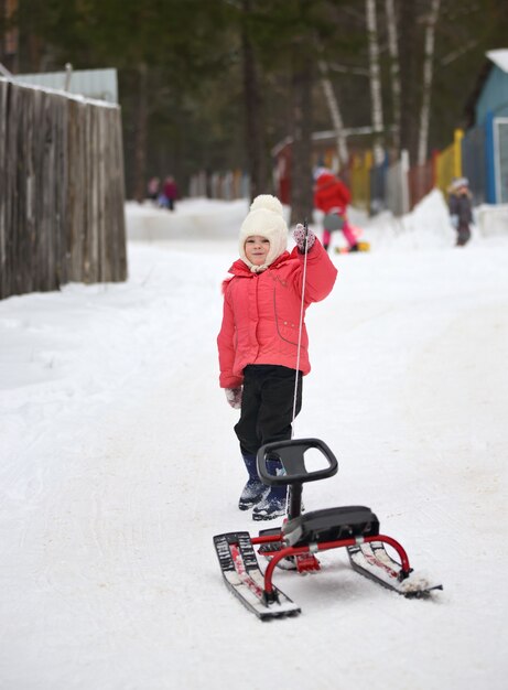 Little girl with sled uphill climbs