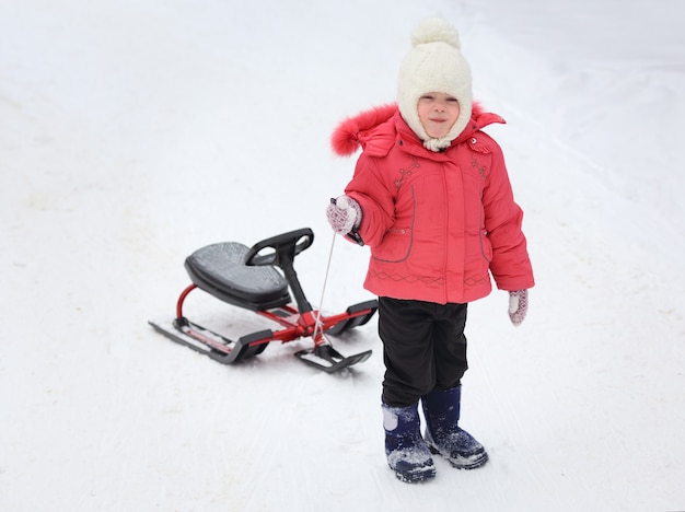 Little girl with sled uphill climbs