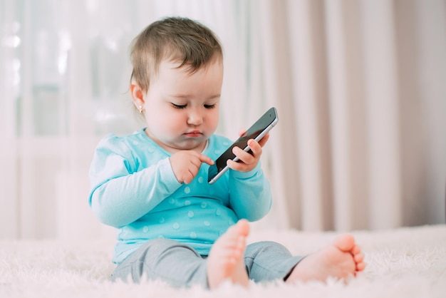 A little girl with a smartphone phone in her hands sits and presses very sweet