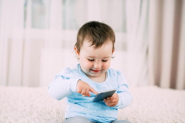 A little girl with a smartphone phone in her hands sits and presses very sweet