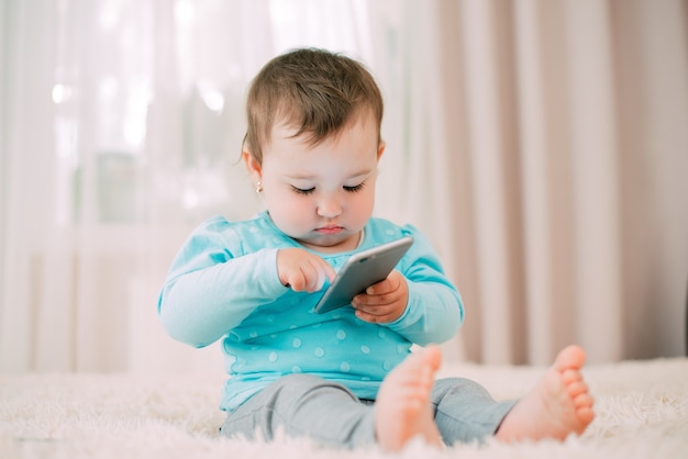 A little girl with a smartphone phone in her hands sits and presses