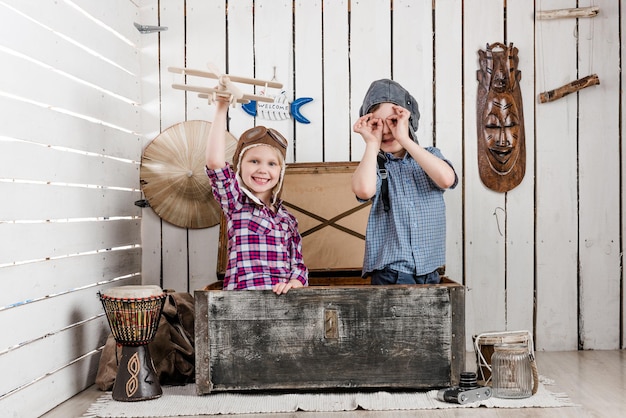 Little girl with wooden plane in hand and boy in pilot hat