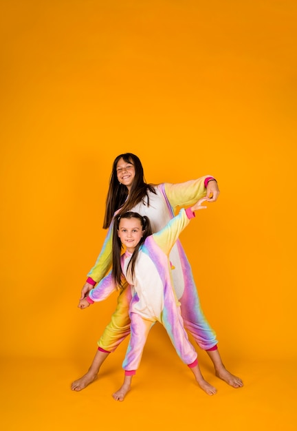 Little girlfriends in kigurumi stand on a yellow background with a place for text