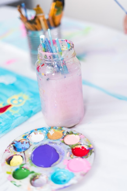 Little girls are painting on canvas with acrylic paint.