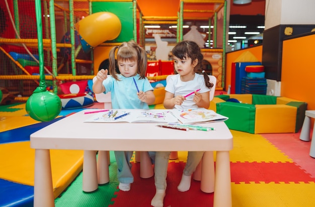 Little girls are sitting at a table and drawing in a children's play center children's creativity