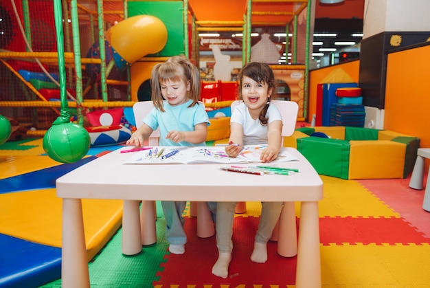 Little girls are sitting at a table and drawing in a children's play center children's creativity