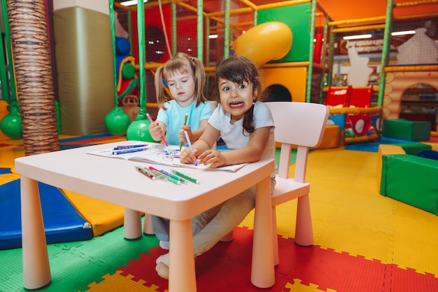 Little girls are sitting at a table and drawing in a children's play center children's creativity