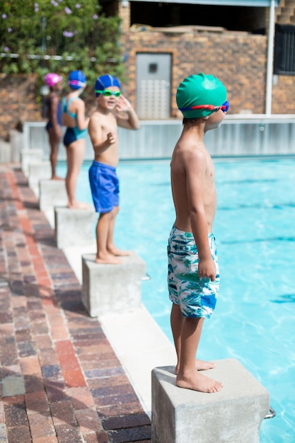 Little girls and boys waiting on start blocks at poolside