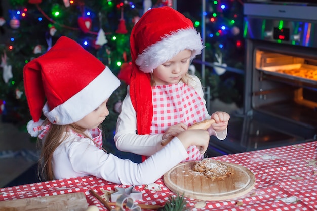 Little girls in Santa hats baking Christmas gingerbread cookies