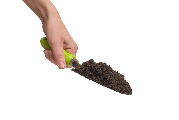 Little green shovel with soil in woman hand isolated on white background.