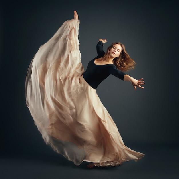 Little gymnast girl in green skirt in the studio gray background