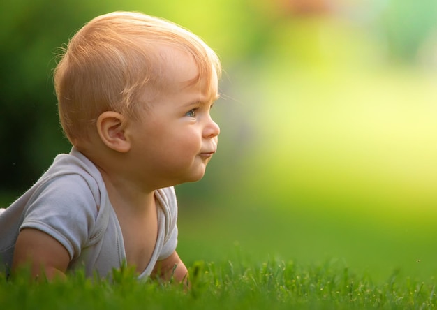 Little happy baby on green grass selective focus