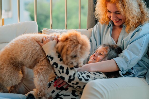 A little happy girl a child with a smile plays on a summer spring vernada at home with mom and a dog