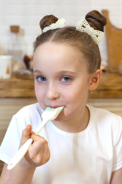 Little happy girl decorates Christmas gingerbread cookies using red glaze selective focus