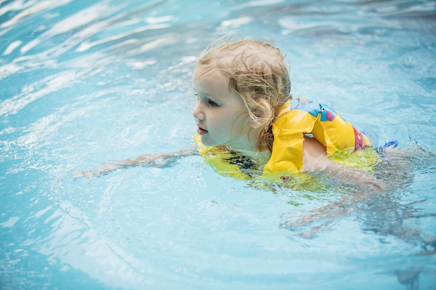 Little happy girl smiling and swimming in the outdoor pool beautiful and happy