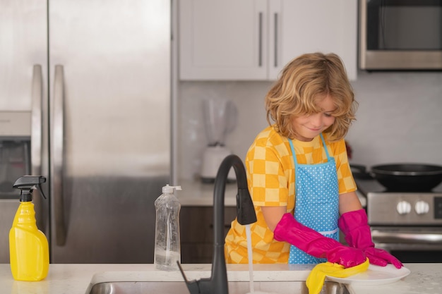 Little housekeeper child washing and wiping dishes in kitchen american kid learning domestic chores