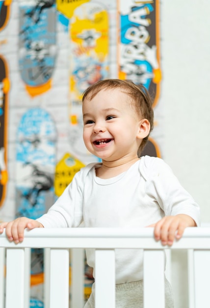 Little infant child near crib in bedroom Small funny kid standing in bed