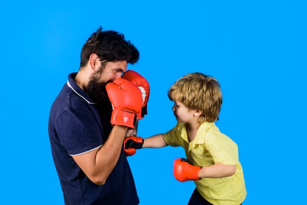 Little kickbox fighter hitting with his coach dad and his son in boxing gloves child and instructor