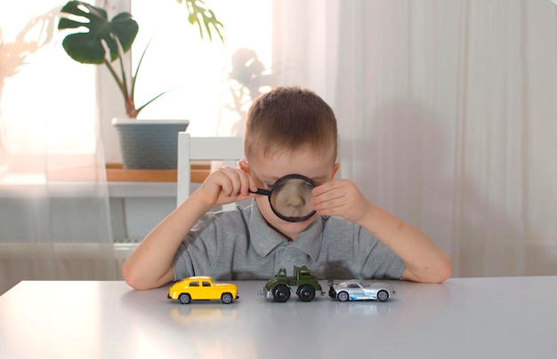 A little kid boy enjoys colorful cars plays with them at a large table Laughing and enjoying his toys