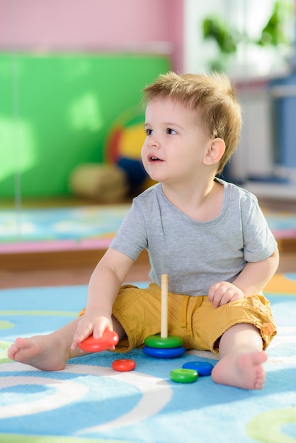 The little kid collects a piraimda sitting on a floor