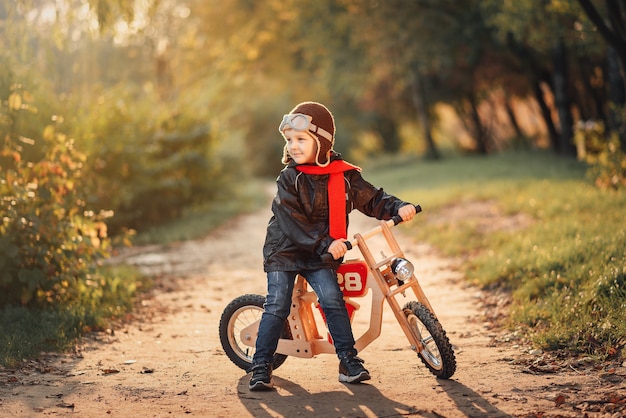 Little kid riding a balance bike in outerwear in autumn