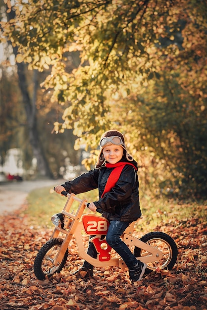 Little kid riding a balance bike in outerwear in autumn