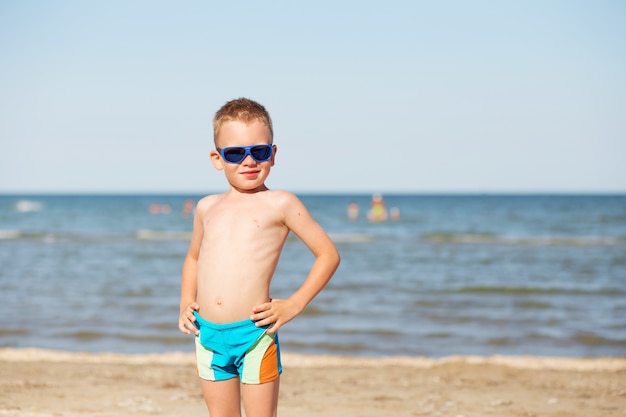 Little kid in sunglasses on a beach