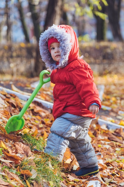 Little kid walks in the park with a shovel