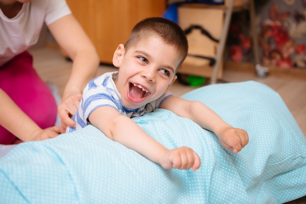 Little kid with cerebral palsy has musculoskeletal therapy by doing exercises  