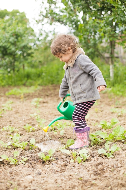 Little kid with watering can in the garden