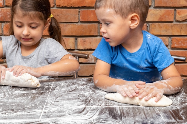 Little kids girl and boy dough, preparing dough for baking