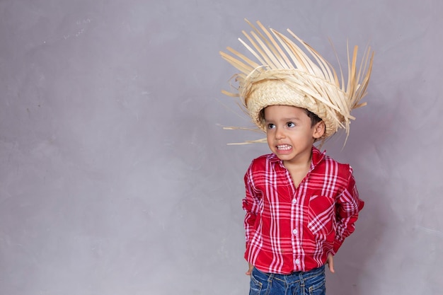 Little man with typical June party clothes Child in typical clothes of famous Brazilian party called Festa Junina in celebration of Sao Joao Beautiful man on gray background